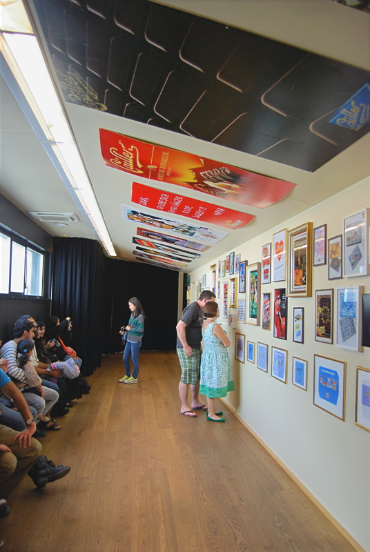 14 - An interior exhibition corridor at the Maison Cailler chocolate factory and museum in Broc, Switzerland, featuring framed historical posters, advertisements, and memorabilia